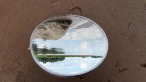 Round Mirror Reflecting River Landscape and Sky on Sandy Shore Stock Footage 340280471