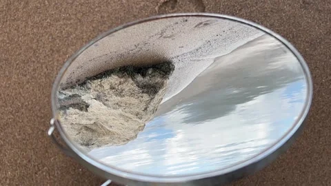Round Mirror on Sand Reflecting Clouds and Large Shoreline Stone Stock Footage 340339055