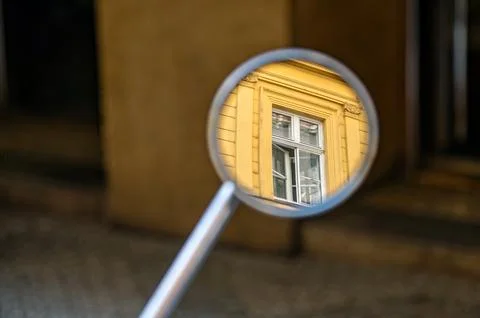 A round mirror shows a reflection of a yellow building in Prague on a sunny d Stock Photos