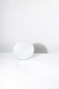 Round mirror on white table with shadow. Minimalism Stock Photos
