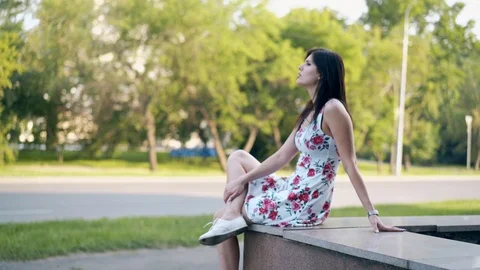 Round motion long haired brunette girl sits on grey parapet Video stock 104324324