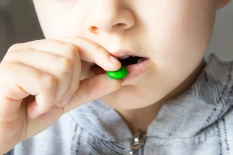 Round, multi-colored, chocolates. The child eats candy. Stock Photos