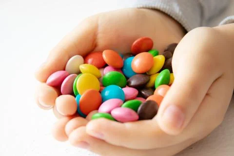 Round, multi-colored, chocolates. A pile of multi-colored candies. A child ho Stock Photos
