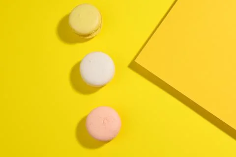 Round multicolored macarons on a yellow background with a shadow on a yellow  Stock Photos
