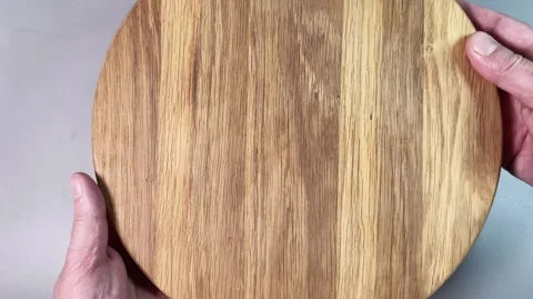 Round oak cutting board in hands on a gray background Stock Footage 342276856