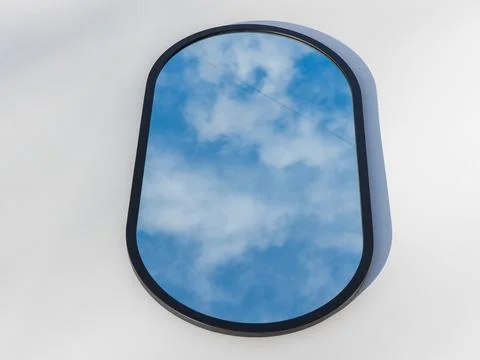 A round or oval mirror with a reflection of the blue sky and white clouds. Close Stock Photos