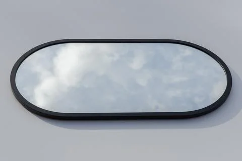 A round or oval mirror with a reflection of the blue sky and white clouds. Close Stock Photos