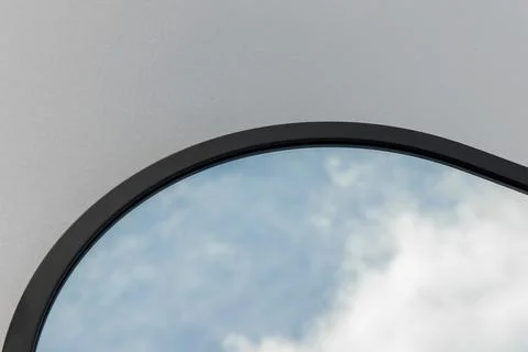 A round or oval mirror with a reflection of the blue sky and white clouds. Close 스톡 사진