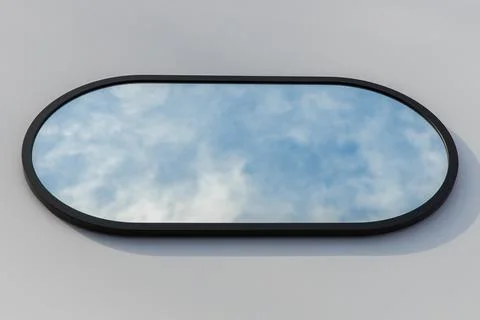 A round or oval mirror with a reflection of the blue sky and white clouds. Close Stock Photos