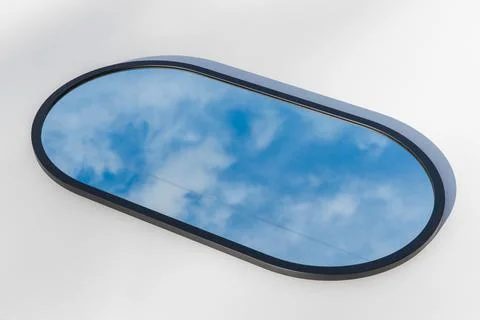 A round or oval mirror with a reflection of the blue sky and white clouds. Close Foto stock