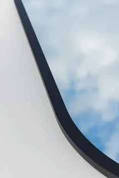 A round or oval mirror with a reflection of the blue sky and white clouds. Close Stock Photos