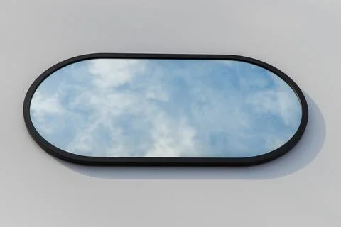 A round or oval mirror with a reflection of the blue sky and white clouds. Close Stock Photos