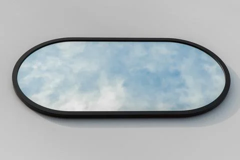 A round or oval mirror with a reflection of the blue sky and white clouds. Close Stock Photos