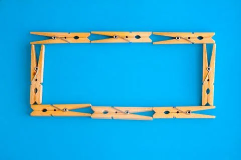 Round or rectangular frame made of wooden clothespins on the blue background. Stock Photos