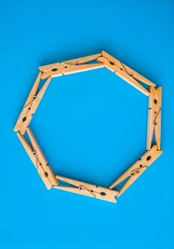 Round or rectangular frame made of wooden clothespins on the blue background. Stock Photos