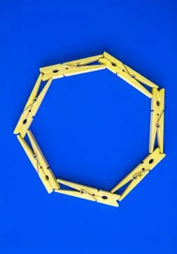Round or rectangular frame made of wooden clothespins on the blue background. Stock Photos
