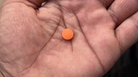 Round Orange Tablet Held in Hand Close-Up | Health and Medicine Concept Stock Footage 321629828