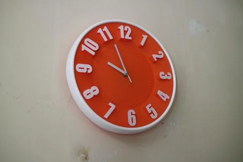Round orange wall clock with hands indicating 10 am Stock Photos