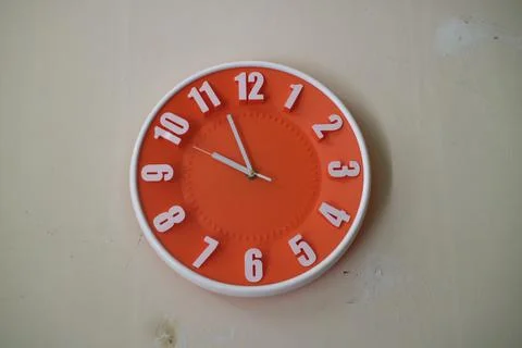 Round orange wall clock with hands indicating 10 am Stock Photos