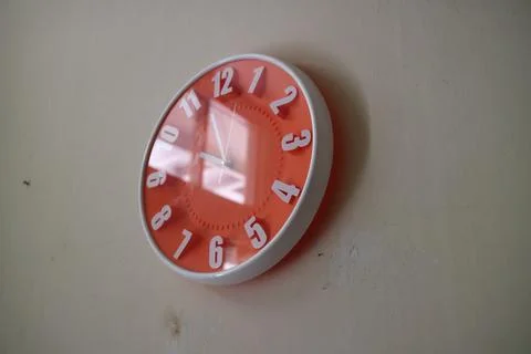Round orange wall clock with hands indicating 10 am Stock Photos