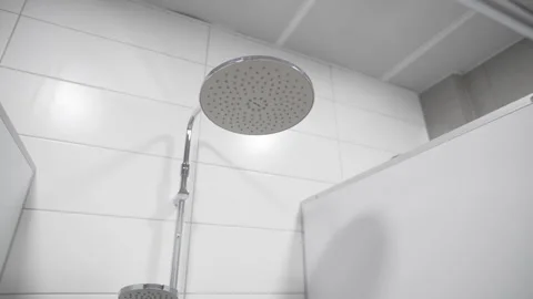 Round overhead shower head in clean tiled public booth 動画素材 323843973