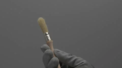 A round paint brush rotates in a hand on a gray background. 스톡 동영상 266892874
