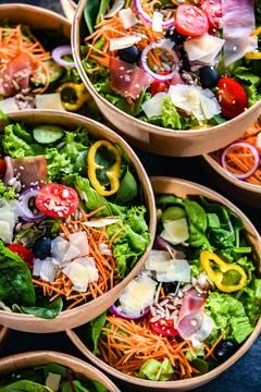 Round paper boxes with pre-packaged vegetable salads ready for sale Stock Photos