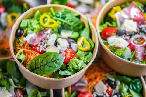 Round paper boxes with pre-packaged vegetable salads ready for sale Stock Photos