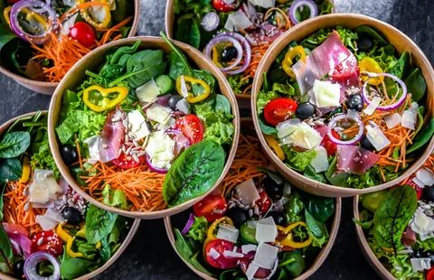 Round paper boxes with pre-packaged vegetable salads ready for sale Stock Photos