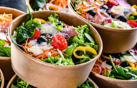 Round paper boxes with pre-packaged vegetable salads ready for sale Stock Photos