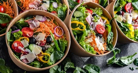 Round paper boxes with pre-packaged vegetable salads ready for sale Stock Photos
