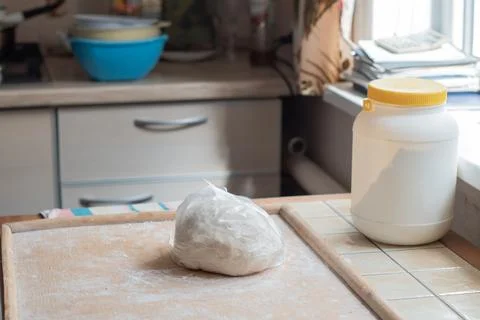 A round piece of raw dough, securely wrapped in clear plastic wrap, sits on a Stock Photos