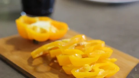 Round pieces of yellow pepper, which lie on a wooden board. Close-up of kitchen. Stock Footage 112939314