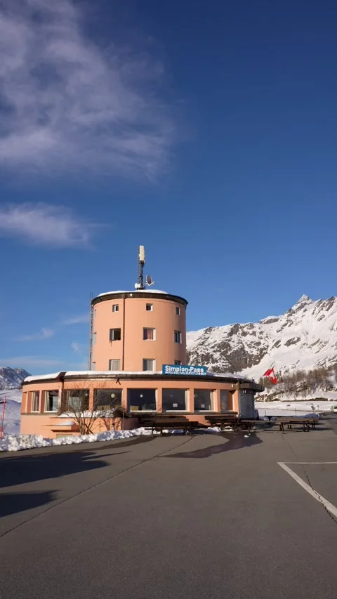 The round pink pass building at the Simplon Pass, Switzerland, stands under a Vídeos de archivo 345953106
