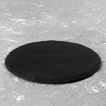 Round plate on table. black dish on gray cement background. copy space Stock Photos