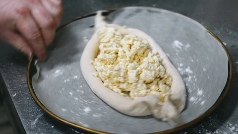 On the round platter, another raw open cheese pie is spinning from the hand of Stock Footage 111812648