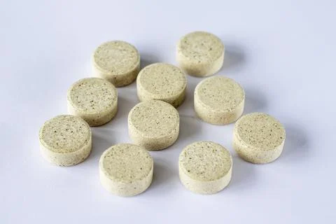 Round puck tablets of irregular beige color on a white background. Suppleme.. Stock Photos