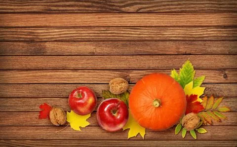 Round pumpkin, apples and walnuts with autumn colorful leaves Stock Photos