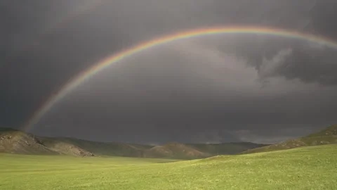 Round rainbow arcs across empty grassland under dramatic storm - Open Space Stock Footage 339826182