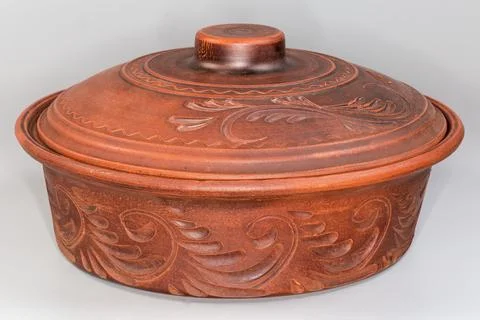 Round red clay roaster with closed lid on gray background Fotos Stock