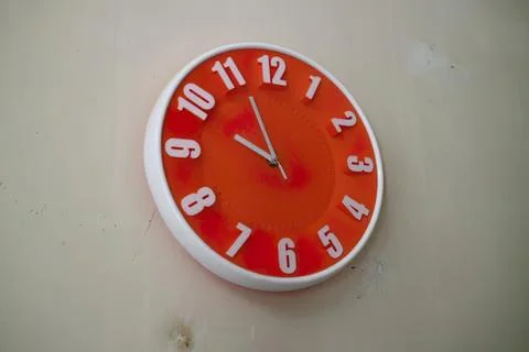 Round red wall clock showing time close to noon Stock Photos