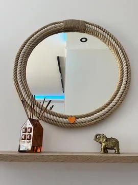 Round Rope Frame Mirror with Cozy Home Decor on Wooden Shelf Stock-Fotos
