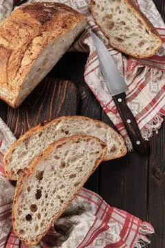 Round rustic bread without kneading cut into pieces on a cutting board on a.. Stock Photos