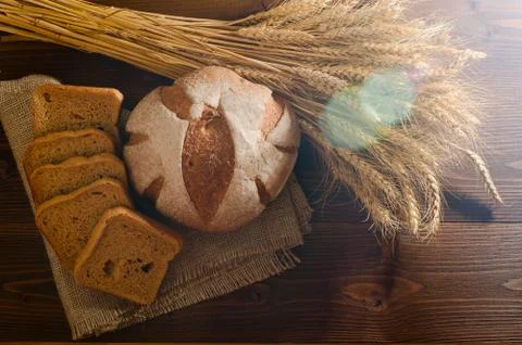 Round rye bread on sacking and a sheaf in the sunlight, solar glare. Wooden b Stock-Fotos