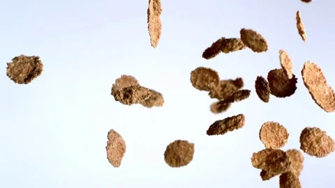 Round shaped cornflakes falling against white background in slow motion Stock Footage 81215127
