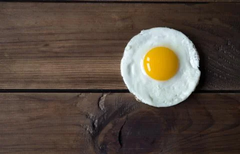 Round shaped fried egg for healthy breakfast on dark wooden backgrond Stock Photos