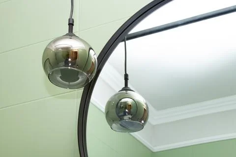 A round shining lamp hangs near the mirror. Selective focus Stock Photos