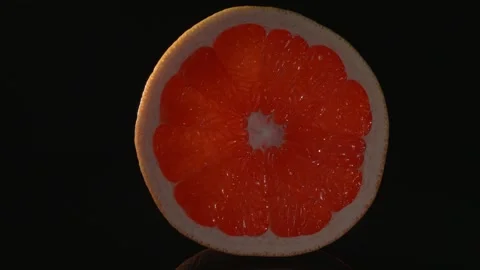 A round slice of grapefruit close-up on a black background. Stockbeeldmateriaal 147132862
