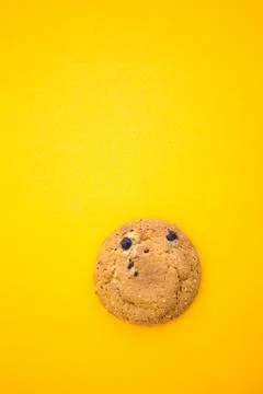 Round smiling cookie on the yellow background with copy space for your text. Stock Photos