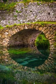 Round stone bridge reflected in river water vertical background Stock Photos